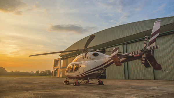 Einsatzfeld Geheimschutz – genua GmbH Helicopter in front of hangar at sunset