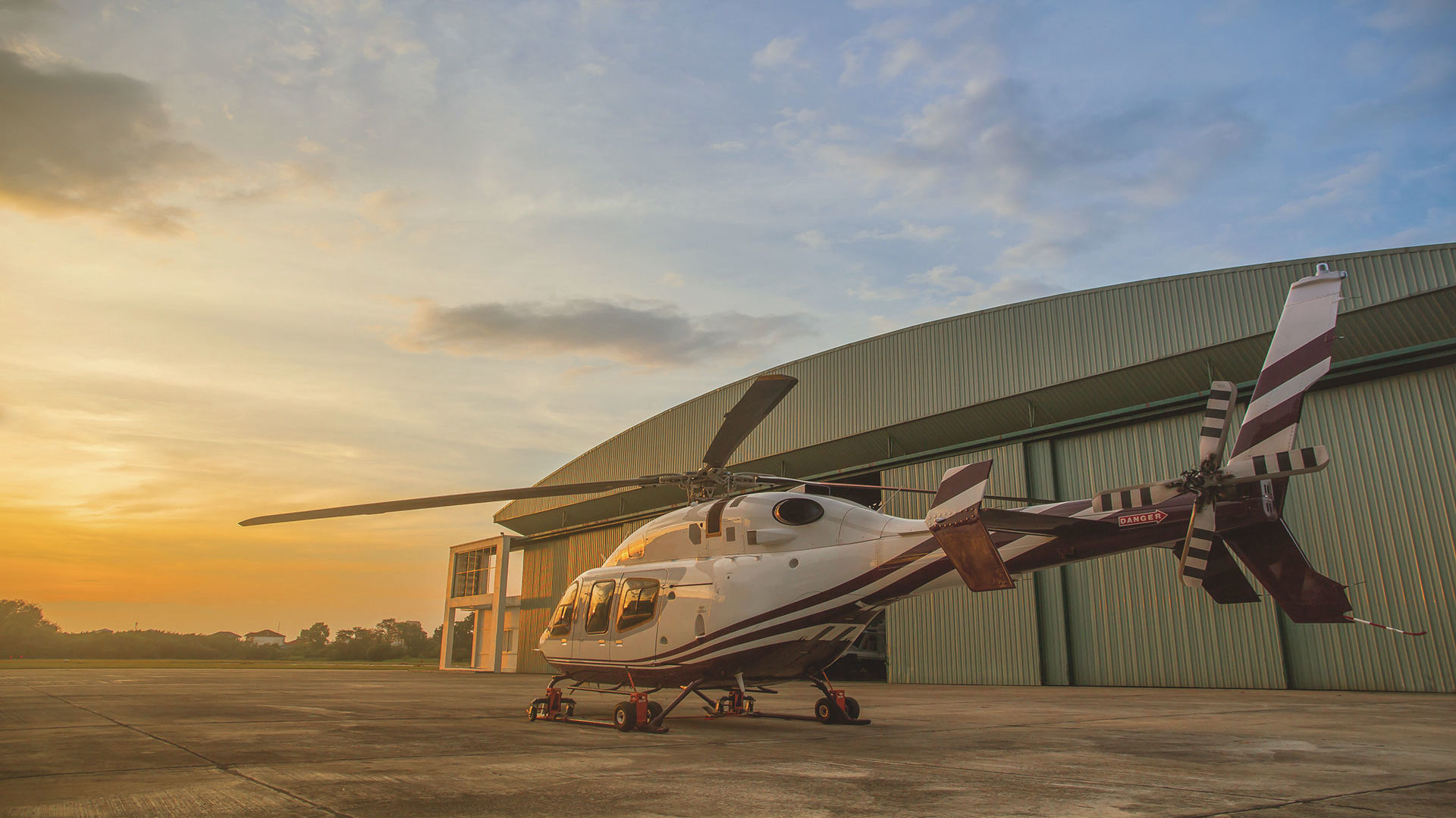 Einsatzfeld Geheimschutz – genua GmbH Helicopter in front of a hanger at sunset